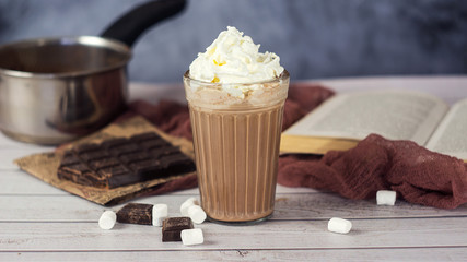 Hot chocolate or cocoa in glass with whipped cream, marshmallow and pieces chocolate