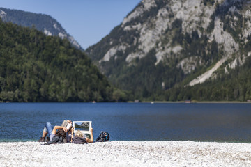 Fototapeta na wymiar Couple reading book and newspaper on lake Leopoldsteiner near Eisenerz in Styria, Austria