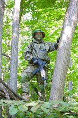 Fototapeta premium Military man in camouflage uniforms and flak jacket with a gun in the woods