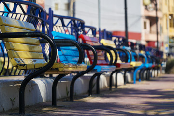 Perspective of colored benches in the city park (blurred in distance)