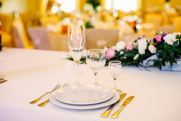 Three crystal glasses stand before white dinner plates