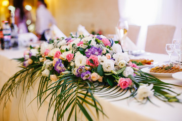 Garland of white and pink roses lies on white dinner table