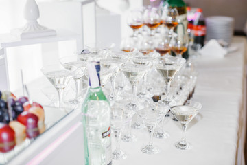 Pyramids of glasses with whisky and martini stand on white dinne