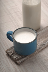 Blue cup with kefir and a bottle on a old stand