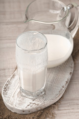 Glass and pitcher of kefir on a wooden stand