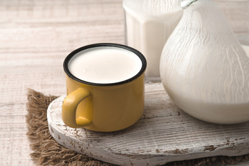 Glass, pitcher, yellow cup of kefir on the napkin and white stand
