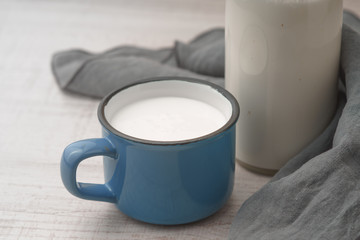 Cup with kefir and a bottle on a wooden table