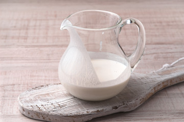 Jug with kefir on a stand on a wooden table