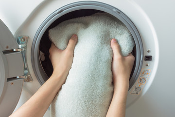 hand and puts the laundry into the washing machine