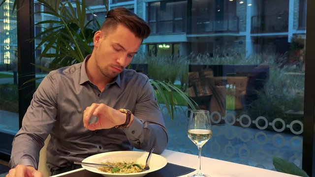 A young, handsome man sits at a table in a restaurant and waits impatiently