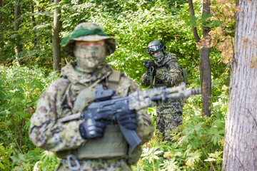 Military man in camouflage with guns in the woods