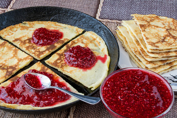 Блины с малиновым вареньем в черной сковороде
