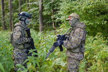 Military man in camouflage with guns in the woods