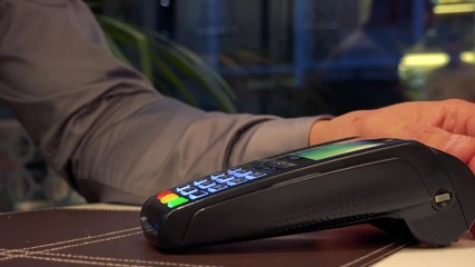 A man puts a credit card to a scanner in restaurant - closeup