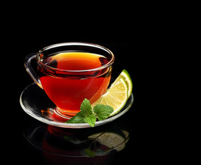 Cup tea with mint and lemon isolated on a black background.