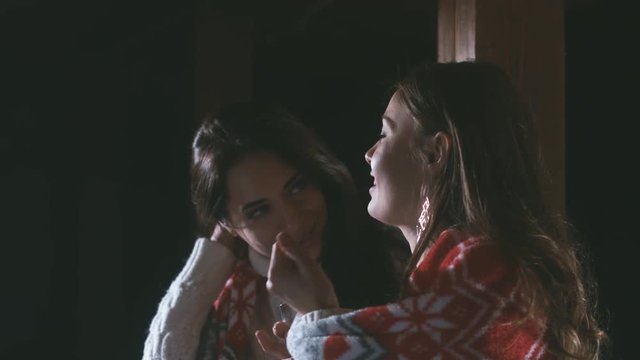 CU 2 young adult females drinking mulled wine having a conversation on a rustic cabin terrace. 4K UHD 60 FPS RAW edited footage