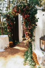 White curtains cover wedding altar decorated with garland of ros