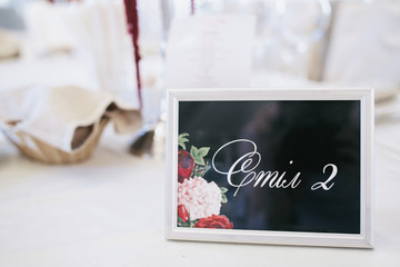 Card with lettering 'Table 2' put in white frame stands on  whit