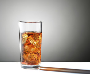 Cold glass of iced tea with ice cube isolated on a gray background 