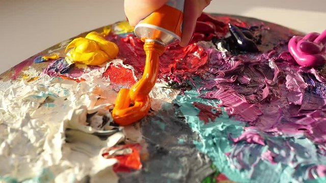 artist squeezes from the tube onto pallets oily orange paint, 4k