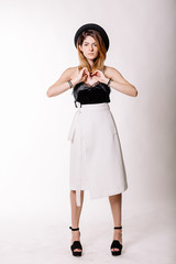 Portrait of girl in Studio in full growth. Black blouse, white skirt, black hat on his head, a beautiful smile. Studio light