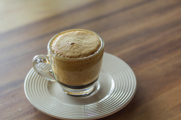 Golden bubble of hot coffee cup placed on a wooden table.