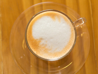 Golden bubble of hot coffee cup placed on a wooden table.