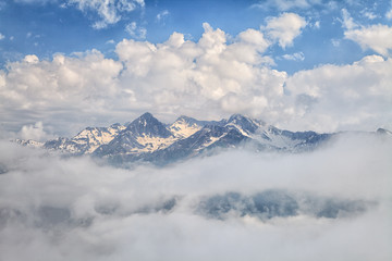 Fototapeta na wymiar Beautiful scenic spring mountain landscape of snowy Aibga mountain peak with blue sky and clouds. Distant mountain tops scenery