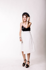 Portrait of girl in Studio in full growth. Black blouse, white skirt, black hat on his head, a beautiful smile. Studio light