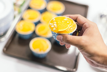 Orange cupcakes in blue baking cup in hand, select focus.