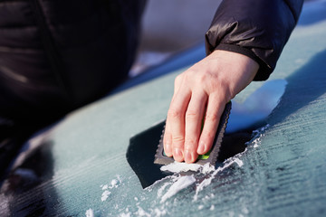 Man scraping ice from the windshield