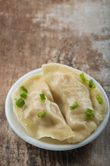 Two boiled dumplings with green onion. Rustic weathered wood background. Copy space 