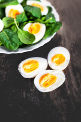 Fresh green spinach baby leaves and boiled eggs cut in a half on