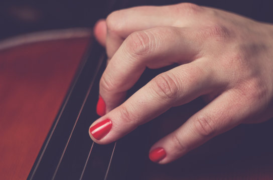 Woman with red nails is playing on cello