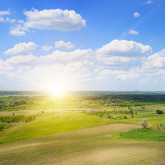 Obraz premium hilly terrain, spring field and sunrise on blue sky