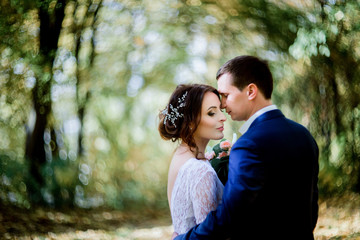 Blurred picture of tall groom hugging bride tender in the forest