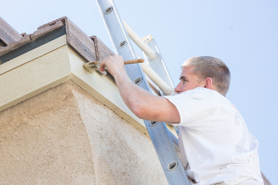 Professional Painter Using A Brush to Paint House Fascia.