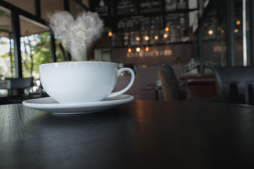 Coffee cup on the table at the coffee shop with heart shaped smoke vintage color tone.