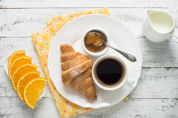 Croissant jam coffee orange juice at white wooden table. Top view with copy space