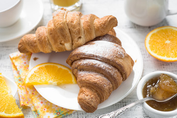Croissant jam coffee orange juice at white wooden table.