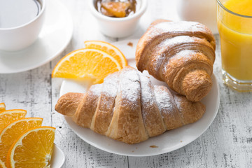 Croissant jam coffee orange juice at white wooden table. breakfast