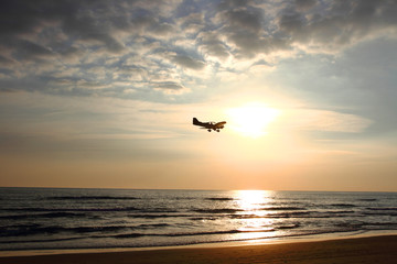 Naklejka na ściany i meble ultralight aircraft flying over the sea at sunset