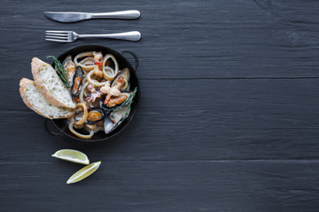 Seafood Stew on dark wood background, top view, copy space