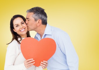 Fototapeta na wymiar Mature man kissing a woman holding red heart