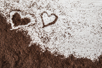 Heart created from ground coffee on the wooden table in the kitchen. Enjoying a coffee break.