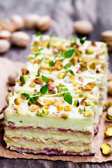 Slices  of layered cake with pistachio on wooden background