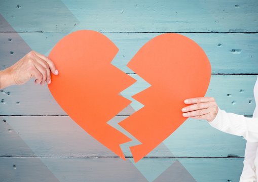 Couple hands holding broken heart against wooden background