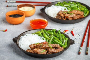 Fried spicy beef with sesame seeds, green beans and rice noodles. Dinner in the Asian style. Selective focus
