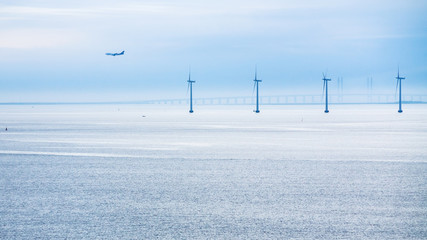 Obraz premium airplane, bridge and offshore wind farm in morning