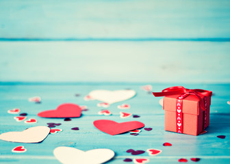 Red gift box and hearts over turquoise wood background